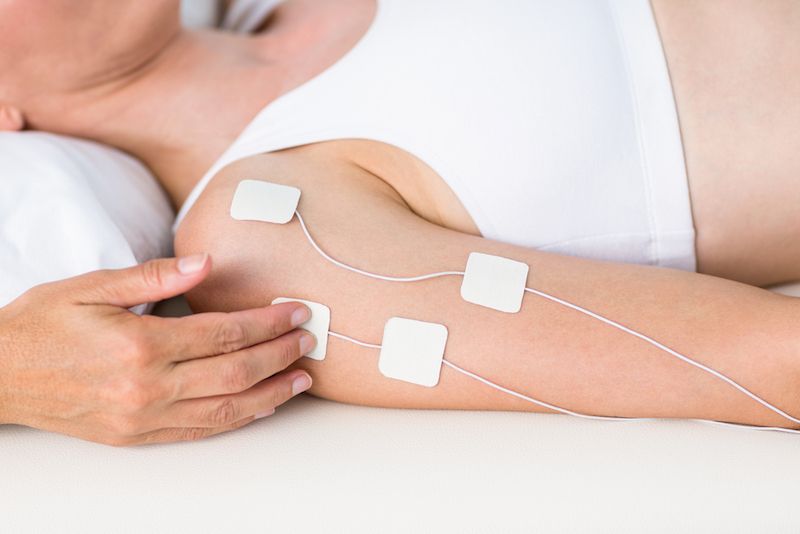 Woman having electrotherapy on white background